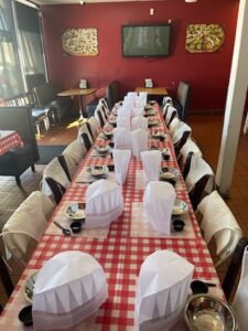Table and chairs with chef hats prepped to make pizzas